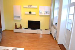 un salon avec une télévision à écran plat sur un mur jaune dans l'établissement Wattwurm, à Wyk auf Föhr