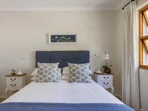 a bedroom with a bed with a blue headboard and pillows at Casa Delfina in Simonʼs Town