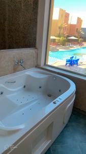 a bath tub in a bathroom with a view of a pool at Al Dora Boutique hotel in Hurghada