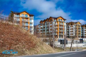 an apartment building on a hill next to a road at Apartamenty BlueSky Kąpielowa 5B - widok na góry, blisko wyciągów i szlaków in Karpacz