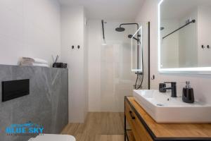 a white bathroom with a sink and a mirror at Apartamenty BlueSky Kąpielowa 5B - widok na góry, blisko wyciągów i szlaków in Karpacz