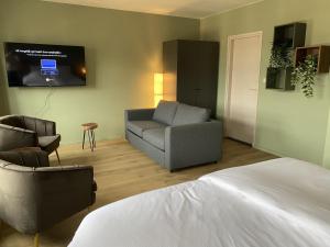 a bedroom with a couch and a chair and a tv at Hotel Courage Gulpen-Wittem in Gulpen