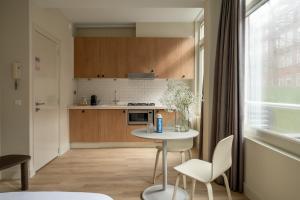 アムステルダムにあるNuma Amsterdam Oosterparkの小さなキッチン(テーブル、椅子付)、窓が備わります。