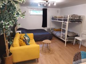 sala de estar con sofá amarillo y literas en Appartement tout confort, en Le Fresne-Camilly