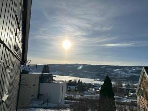 uma vista de uma cidade nevada com o sol no céu em Stort hus sentralt i Lillehammer em Lillehammer