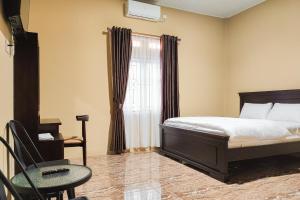 a bedroom with a bed and a chair and a window at RedDoorz Syariah near Telanaipura Jambi in Jambi