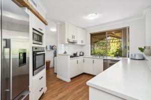 a kitchen with white cabinets and a stainless steel refrigerator at Silver Sands Holiday & Beach House in Mandurah