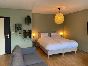 sypialnia z białym łóżkiem i kanapą w obiekcie Hotel Courage Gulpen-Wittem w mieście Gulpen