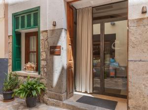 a facade of a store with green doors and plants at Ca’s Cuscanti in Sóller