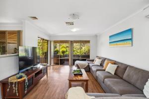 a living room with a couch and a flat screen tv at Silver Sands Holiday & Beach House in Mandurah