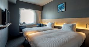熊本市にあるグリッズプレミアムホテル熊本の大型ベッドとテレビが備わるホテルルームです。