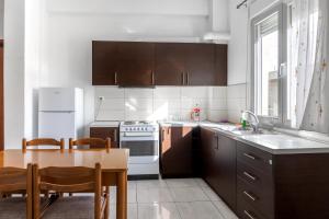 cocina con armarios de madera y mesa y cocina con fogones en King home Larissa city, en Larisa