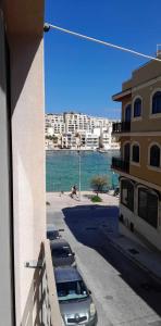 Seafront akwador في Il-Ħamrija: اطلاله على شارع فيه سيارات متوقفه بجانب مبنى