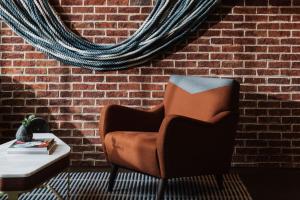 a brown chair sitting next to a brick wall at The Alida, Savannah, a Tribute Portfolio Hotel in Savannah