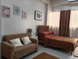 a living room with a couch and a bed at Cozy studio unit in a condominium in Iloilo City