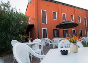Polesine Camerini的住宿－Agriturismo La Violetta，一座橙色的建筑,配有白色的桌椅和雨伞