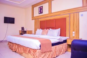 a large bed with a wooden headboard in a room at Owee Hotel Exclusive Apartments & Suites in Lagos