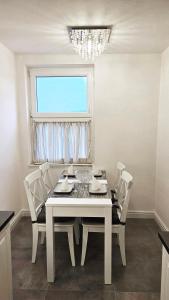 einen weißen Esstisch mit weißen Stühlen und einem Fenster in der Unterkunft Bridge View Apartment Lapad in Dubrovnik