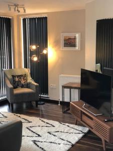 een woonkamer met een televisie en een stoel bij Riverside Penthouse Apartment in Londonderry County Borough
