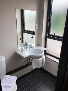 een witte badkamer met een wastafel en een spiegel bij Riverside Penthouse Apartment in Londonderry County Borough