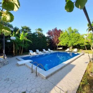 a swimming pool with lounge chairs next to a house at Vila Marija in Podgorica