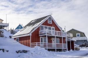 una casa rossa con neve sul tetto di 4-bedroom house with sea view and hot tub a Ilulissat