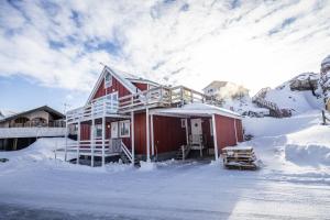 une grande maison rouge dans la neige dans l'établissement 4-bedroom house with sea view and hot tub, à Ilulissat