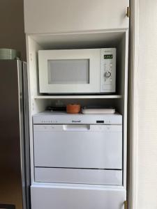 a microwave sitting on top of a white oven at Le grand Louis, hypercentre in Cherbourg en Cotentin