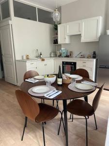 een keuken met een houten tafel met stoelen en een fles wijn bij Le grand Louis, hypercentre in Cherbourg en Cotentin