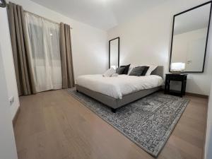 une chambre blanche avec un lit et un grand miroir dans l'établissement LE PARADIS BLANC, à Annecy