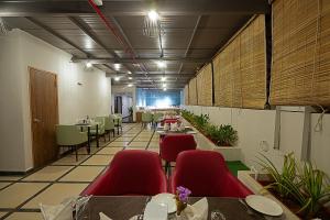 a restaurant with red chairs and tables in a room at Grand Continent Malleshwaram A Sarovar Portico Affiliate Hotel in Bangalore