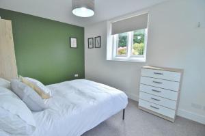 a bedroom with a white bed and a green wall at Trade Digs Ryeleaze Road in Stroud