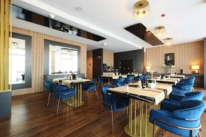 a dining room with tables and blue chairs at Hotel Artemis in Oradea