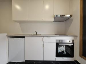 uma cozinha com armários brancos, um lavatório e um fogão em Magnifico apartamento en Canelas em Portonovo