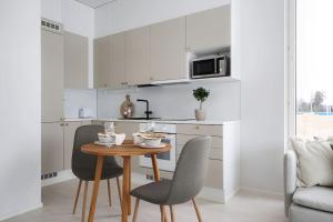 a kitchen with a table and chairs in a kitchen at LadyCrane apartment, sauna and parking in Kirkkonummi