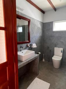 a bathroom with a sink and a toilet and a mirror at Bali Villa Mirissa in Mirissa