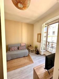 een woonkamer met een bank en een tv bij 11 Trachel - Charmant T2 spacieux à proximité de gare Thiers in Nice