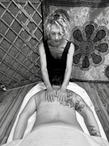 un homme qui se couche dans un lit avec un tatouage dans l'établissement Spa Les Jardins De Chiron Lodges et Tiny House dans le sud, à Sauve