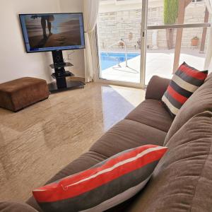 a living room with a couch and a tv at Villa Athena in Peyia