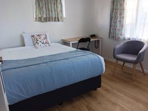 um quarto com uma cama, uma cadeira e uma secretária em Melville Guest House near Waikato Hospital em Hamilton