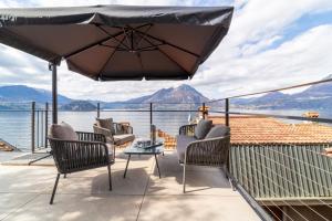 eine Terrasse mit Stühlen und einem Sonnenschirm mit Blick auf das Wasser in der Unterkunft La Risorgente by Wonderful Italy in Varenna