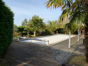 een zwembad met een houten terras en een palmboom bij Mon Hacienda in Caumont