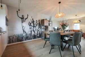 a dining room with a table and a painting of people jumping at Hello Zeeland - vakantiewoning Knuitershoek 70 