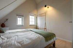 a bedroom with a large white bed and windows at Hello Zeeland - vakantiewoning Knuitershoek 70 