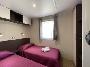 a room with two beds with purple sheets and a window at Campeggio Villaggio Sos Flores in Tortolì