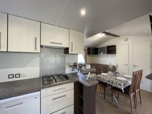 une cuisine avec des placards blancs, une table et une salle à manger dans l'établissement Campeggio Villaggio Sos Flores, à Tortolì