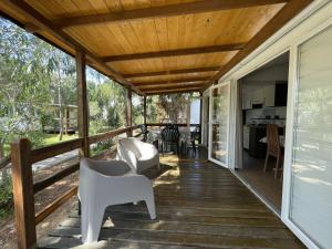 una veranda con sedie bianche e soffitto in legno di Campeggio Villaggio Sos Flores a Tortolì