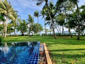 a swimming pool in a park with palm trees at Amatapura Beachfront Villa 12, SHA Certified in Ao Nam Mao