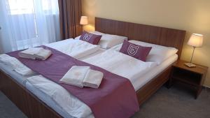 a large bed in a hotel room with towels on it at Hotel Eminent in Stupava