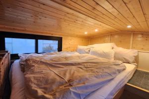 a large bed in a room with a wooden ceiling at Behagliches OFFGRID Tiny House - Escape to Nature in Sankt Pölten